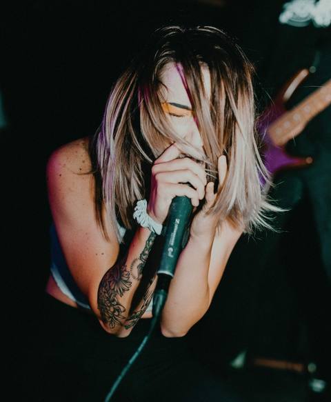 A singer leaning into the microphone, hair falling across her face