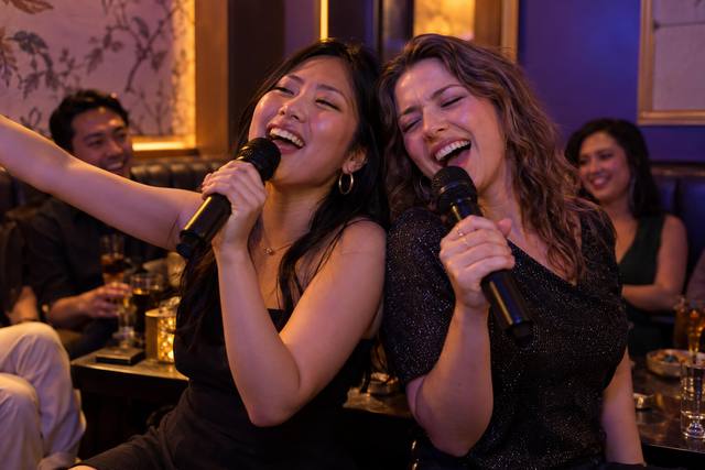 Two friends singing a duet together in a warmly lit karaoke lounge