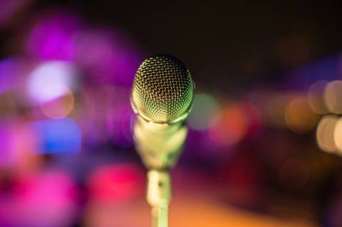 A vintage microphone in front of glowing pink and purple lights